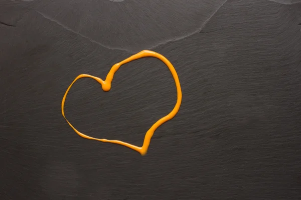 Hjärtat av apelsinsås på den svarta stenen — Stockfoto