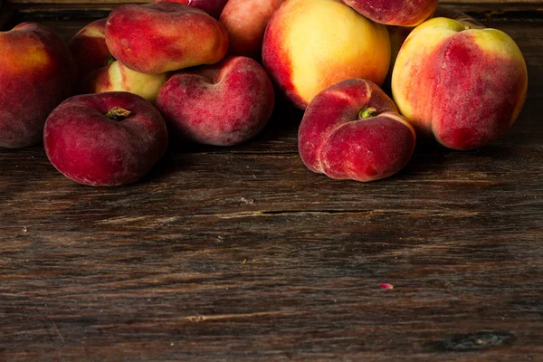Плоский стиглий персик і звичайний персик на дерев'яному фоні — стокове фото