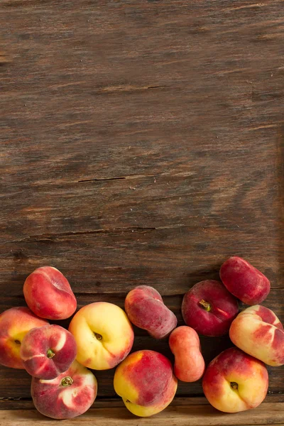 Плоский стиглий персик і звичайний персик на дерев'яному фоні — стокове фото