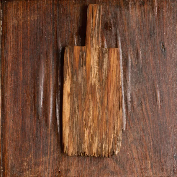 Vieja tabla de cortar de madera sobre un fondo de madera — Foto de Stock