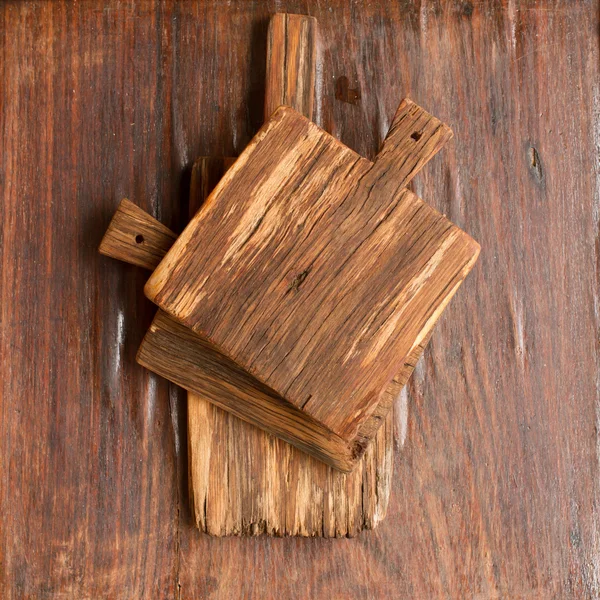 Vieja tabla de cortar de madera sobre un fondo de madera —  Fotos de Stock