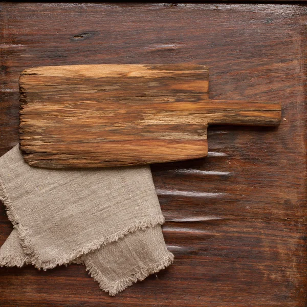 Vieja tabla de cortar de madera sobre un fondo de madera —  Fotos de Stock