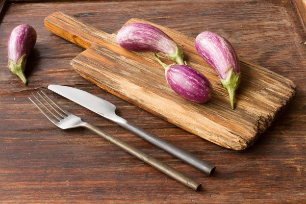 Berenjena pequeña en una tabla de cortar de madera —  Fotos de Stock