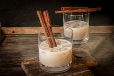 Irish cream liqueur in a glass with ice and cinnamon clipart