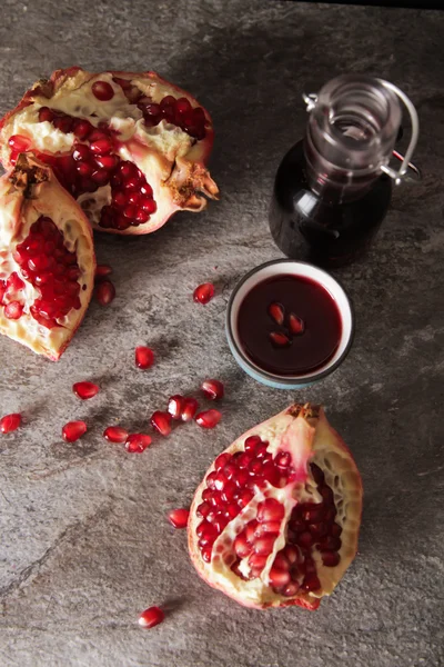 Succo di melograno in un cerchio blu e succoso granato rosso. su un gr — Foto Stock