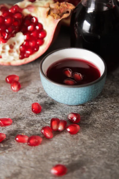 Succo di melograno in un cerchio blu e succoso granato rosso. su un gr — Foto Stock