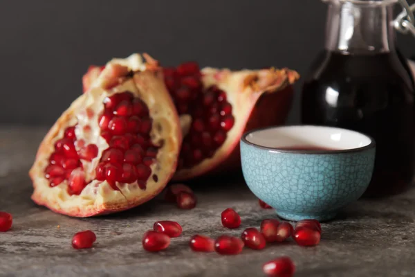 Pomegranate juice in a blue circle and juicy red garnet. on a gr — Stock Photo, Image