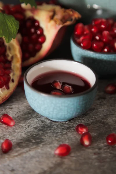 Succo di melograno in un cerchio blu e succosa melograno rosso e — Foto Stock