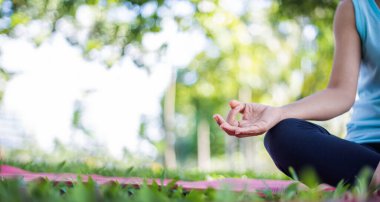 Genç bir kadının doğada yoga yaptığı sahneler. Gün batımında altın ışıkta yeşil çimlere otur. Egzersiz yapmak ve sağlığınızı korumak için iletişim kurun. Çimenlerin yeşil rengi taze hissettirir..