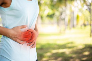 Genç bir kadının karın ağrısı. Beyaz bir arka planda önden çekilmiş. Karın ağrısı. Kadınların adet sancısı.