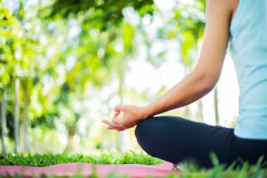 Genç bir kadının doğada yoga yaptığı sahneler. Gün batımında altın ışıkta yeşil çimlere otur. Egzersiz yapmak ve sağlığınızı korumak için iletişim kurun. Çimenlerin yeşil rengi taze hissettirir..