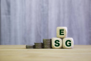 Yığınla madeni para içeren ESG blokları sürdürülebilir yatırım, sorumlu iş ve çevre, sosyal ve yönetim uygulamaları yoluyla uzun vadeli değer oluşturulmasını temsil etmektedir..