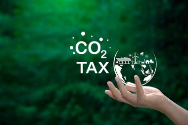 Karbon vergisi kavramını ve sürdürülebilir yeşil ekonominin desteklenmesindeki rolünü temsil eden CO2 vergi simgesiyle el ele tutuşan bir dijital arayüz.