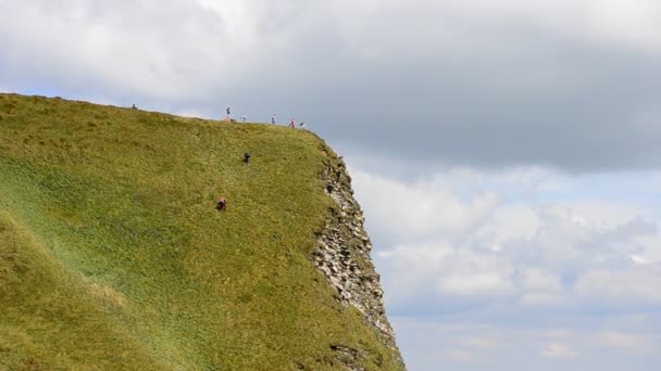 Mensen met rugzakken die in de zomer een berg beklimmen — Stockvideo