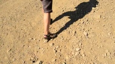 Taşlı yolda yürüyen sandaletli bir kadının ayakları