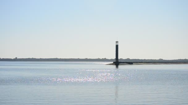 La superficie del agua azul brilla y brilla al sol con el faro — Vídeos de Stock