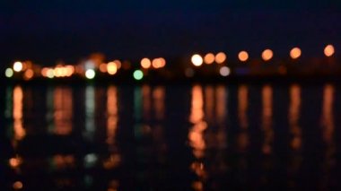 Gece trafik odaklanmamış şehir ışıkları ile suya yansıyan.