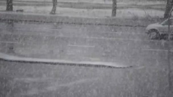 Těžký sníh padá na pozadí silnice s auty jízdy — Stock video