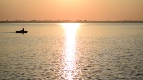 Silhouette d'homme ramant dans un petit bateau en caoutchouc à l'aube — Video