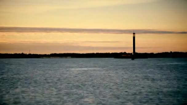 Leuchtturm bei Sonnenaufgang über dem Wasser und eine Bootsilhouette auf der Wasseroberfläche — Stockvideo