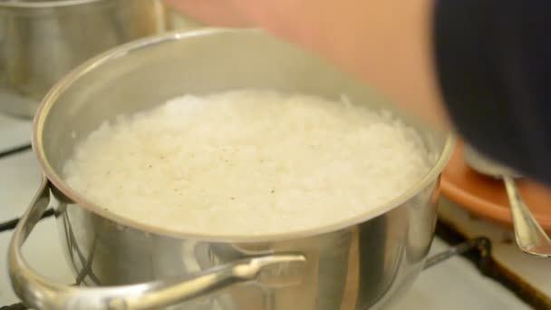 Peper en zout aan rijst koken in steelpan toe te voegen — Stockvideo