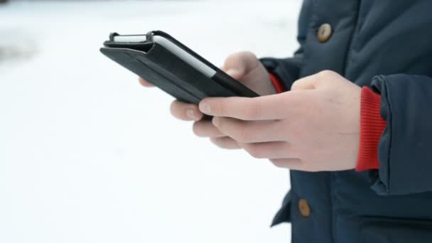 Närbild av kaukasiska tonåring använder tablet utomhus på vintern — Stockvideo