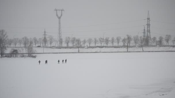 Группа людей идет по льду, покрытому снегом, к дамбе — стоковое видео