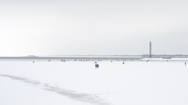 Two winter fishermen walking toward a large group of anglers — Stock Video