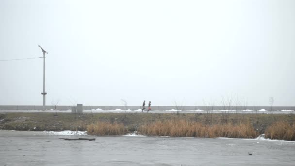 Tres personas trotando en invierno en una carretera — Vídeos de Stock