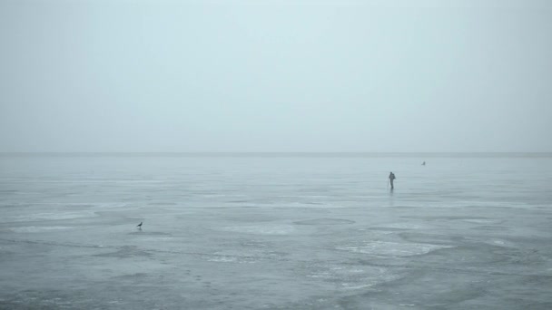 Зимний рыбак проделывает дыру во льду ледорубом — стоковое видео