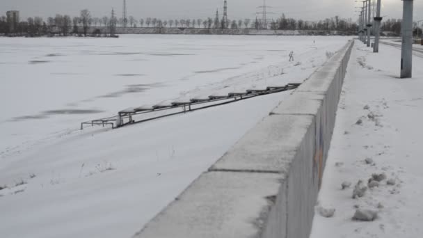 Man in white clothes climbing a dike of frozen water storage reservoir — Stock Video