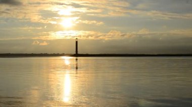 Şafakta deniz feneri arka plan üzerinde kuş uçar