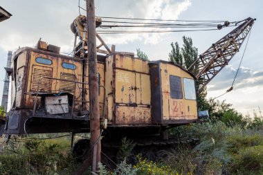 Bir yaz günü açık hava sanayi bölgesinde kaya madenciliği için bir kazıcı duruyor..