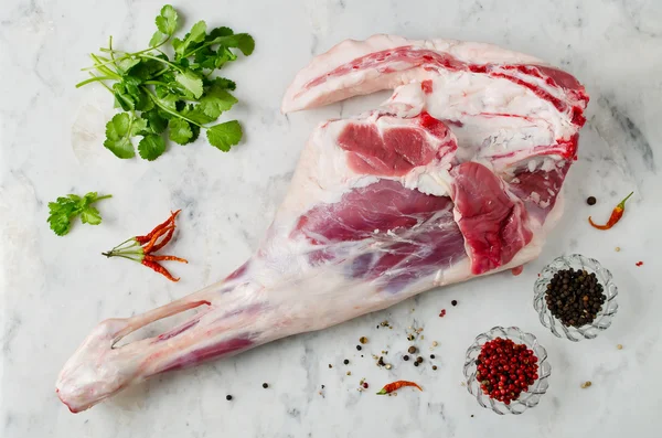 Raw leg of lamb on a marble table — Stock Photo, Image