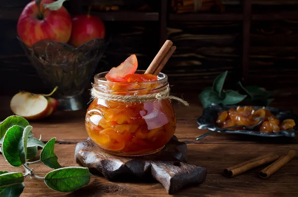 Homemade sweet apple jam with cinnamon. Jam in a jar on a wooden table.