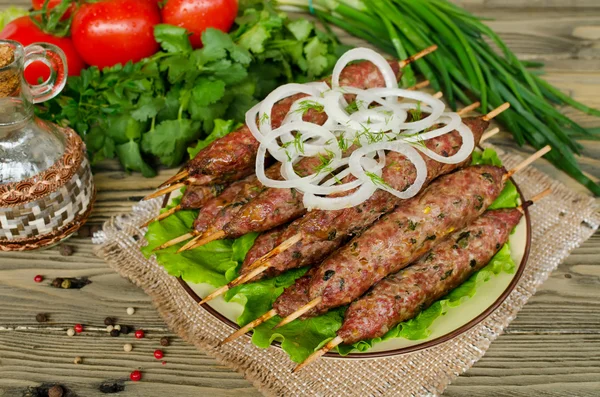 Kebabs grelhados em espetos de madeira e legumes frescos — Fotografia de Stock