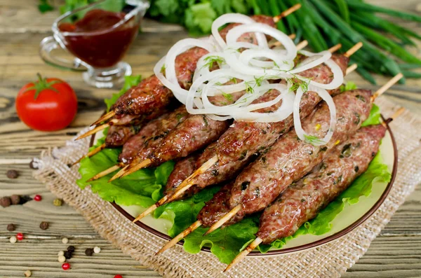 Gegrilde kebabs op houten spiesen en verse groenten — Stockfoto