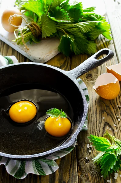 Huevos revueltos con ortigas en la sartén sobre mesa de madera —  Fotos de Stock