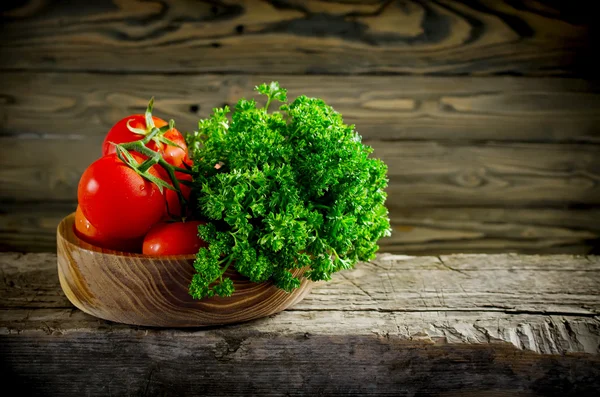 Färska grönsaker och örter, tomater och persilja på en trä flik — Stockfoto