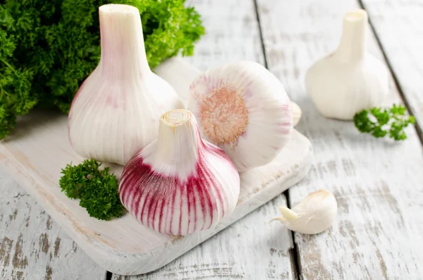 Ail et un bouquet de persil sur une table blanche — Photo