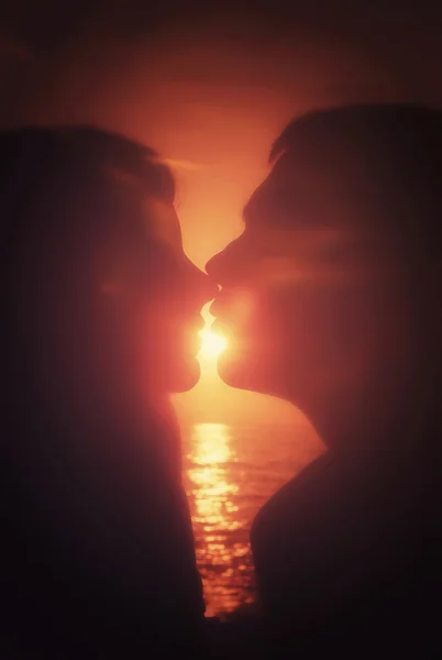 Silhouetten paar kussen bij zonsondergang Rechtenvrije Stockfoto's
