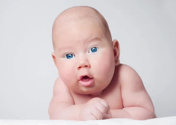 Verrast blauwogige babyjongen op zoek naar camera Stockfoto