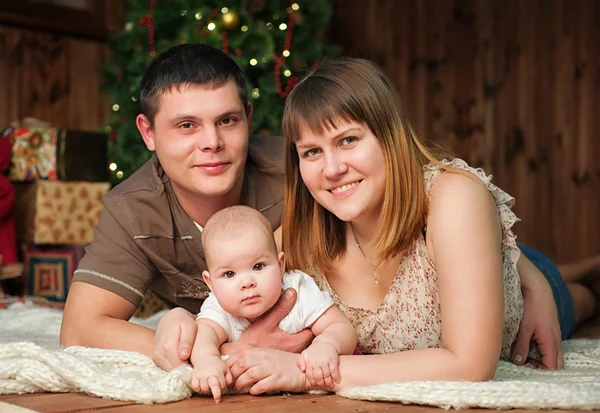 Family with little 7 months girl in front of Christmas tree at wooden house — Stock Photo, Image