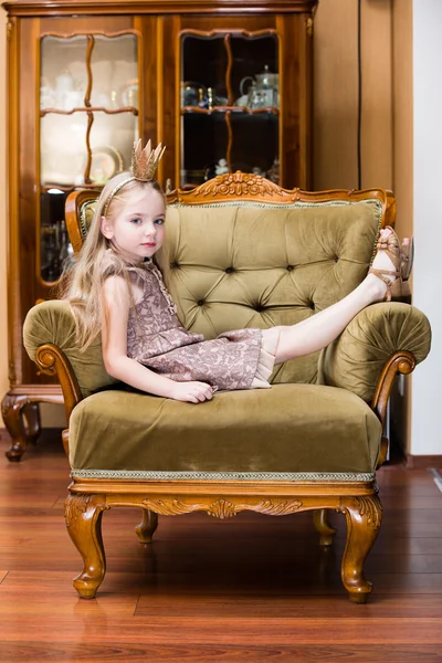 Μικρό κορίτσι ξανθιά μαλλιά φορώντας στέμμα στέκεται στην καρέκλα του — Φωτογραφία Αρχείου
