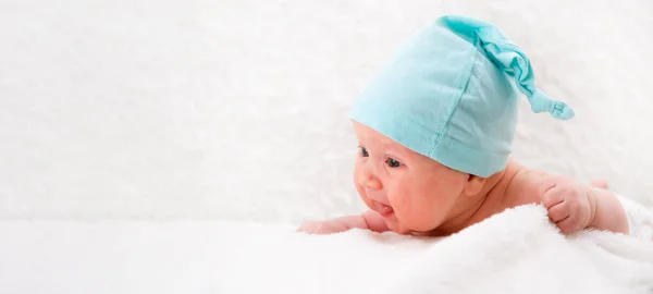 Un bebé de un mes con una gorra azul yace sobre su estómago y mira al mundo. Concepto familiar. Burla en la cabecera. Copycpace —  Fotos de Stock