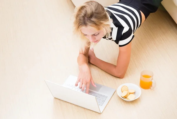 Girl looks in the laptop from the couch — Stock Photo, Image