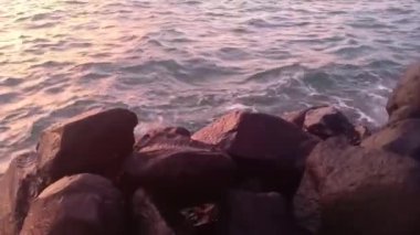 Sakin deniz manzaralı, öğleden sonra dalgalı, gün batımlı.