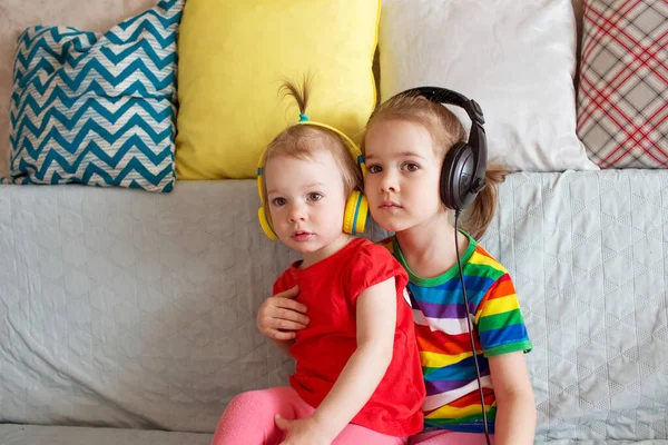 children learn english with headphones. Two girls listen to music on headphones,