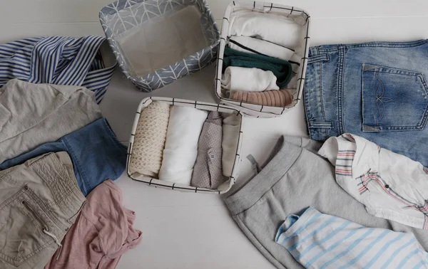 A group of organic cotton clothing set on a white table is ready to be folded into white baskets.The concept of closet organization. Colors in the Scandinavian style. Using the Komari method