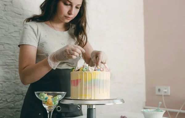 A pastry chef makes a wedding cake with her own hands and puts colorful decorations on the cakes with cream. Preparation for the celebration